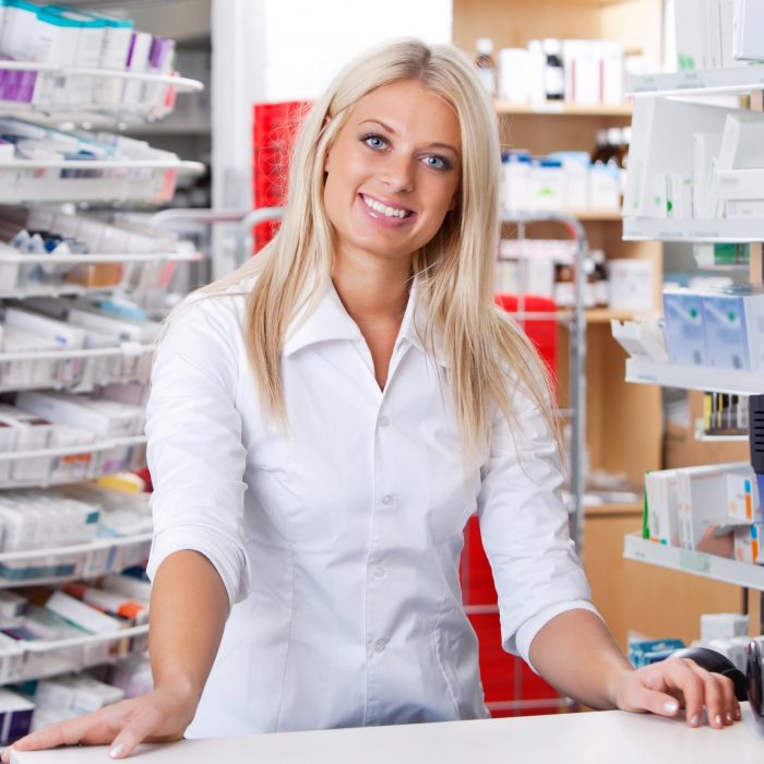 Portrait of smiling female pharmacist standing at checkout counter