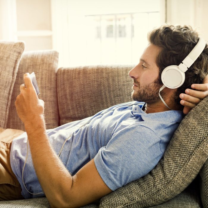 Man on couch watches a movie on mobile phone